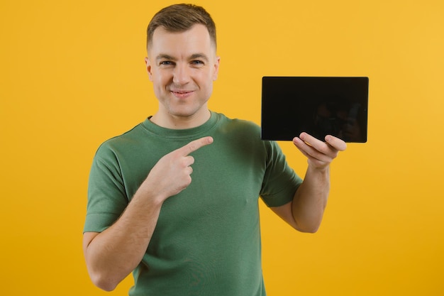 Cheerful young man using digital tablet sur fond jaune