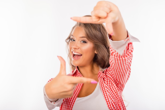 Cheerful young woman gesturing doigt cadre et souriant