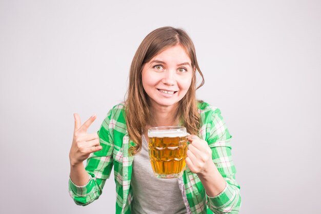 Cheerful young woman holding a beer mug plein de bière et souriant sur fond blanc.