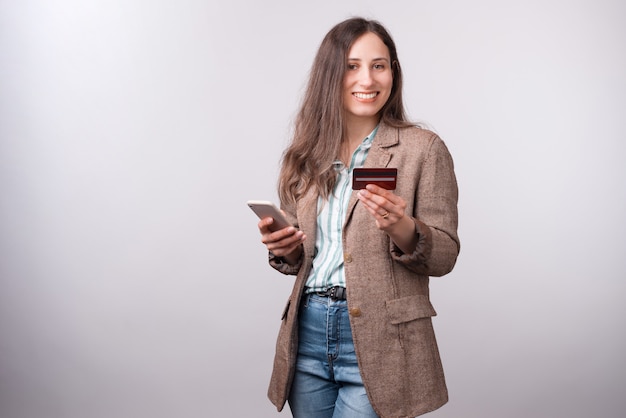 Cheerful young woman in casual montrant sa nouvelle carte de débit et souriant.