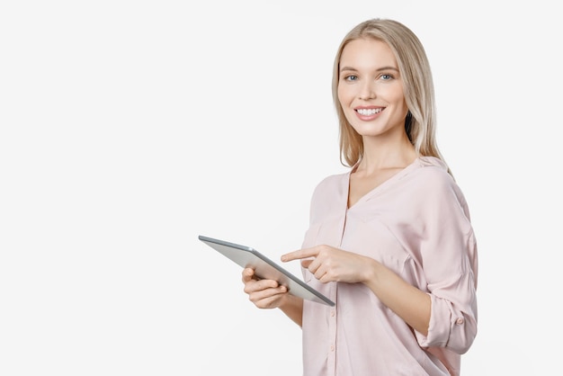 Cheerful young woman looking at camera à l'aide d'un ordinateur tablette sur fond blanc