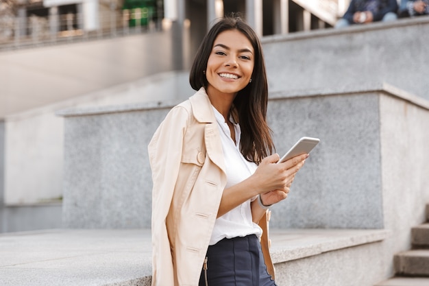 Cheerful young woman using mobile phone