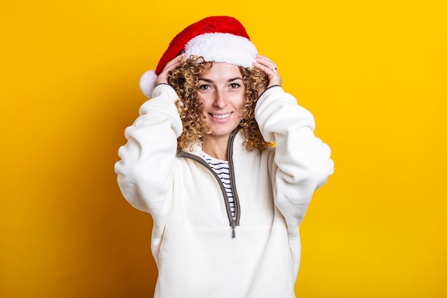 Cheerful young woman wearing santa claus hat sur fond jaune.