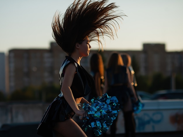 Cheerleaders dansant sur le toit au coucher du soleil contre le paysage de la ville