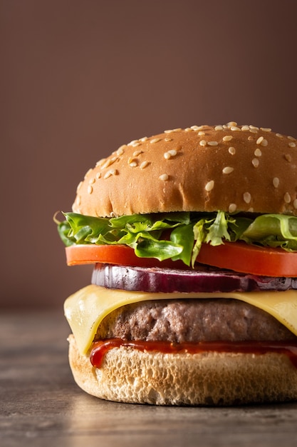 Cheeseburger avec boeuf, tomate, laitue et oignon sur table en bois