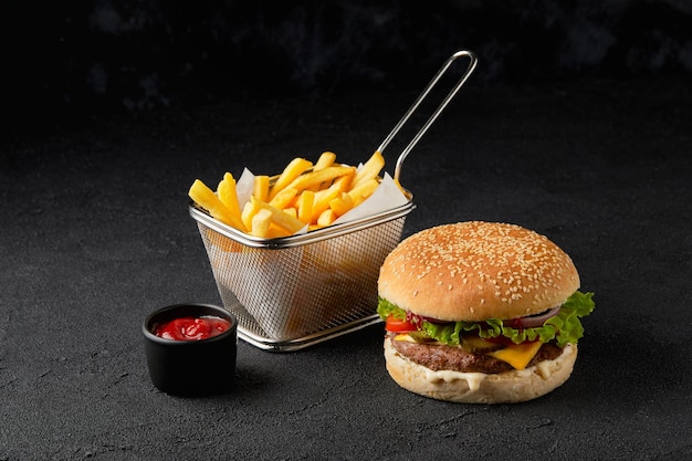 Cheeseburger classique et frites sur fond noir restaurant de restauration rapide