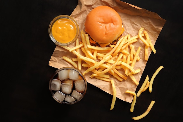 Cheeseburger et frites sur papier brun vue de dessus Burger frites cola avec de la glace