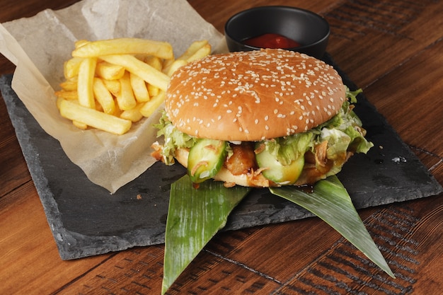 Cheeseburger avec frites et sauce sur fond de bois marron