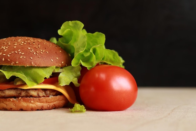 Cheeseburger et tomate sur fond sombre espace vide d'un côté Restauration rapide