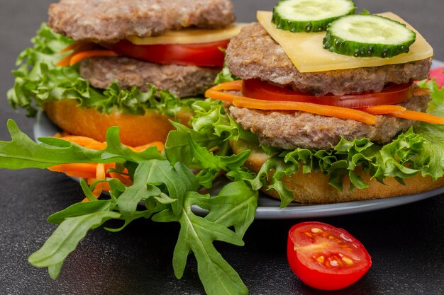 Cheeseburgers aux verts de concombre hachés oignons et carottes sur plaque grise