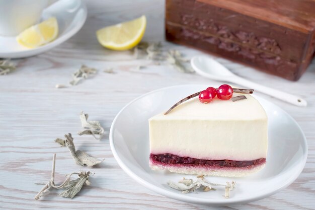 Cheesecake aux fruits rouges sur plaque blanche sur table en bois blanc.