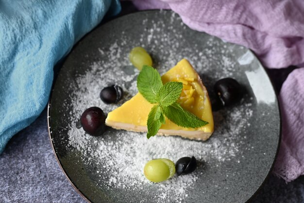 cheesecake dessert sur une assiette avec du raisin dans un restaurant avec une feuille de menthe