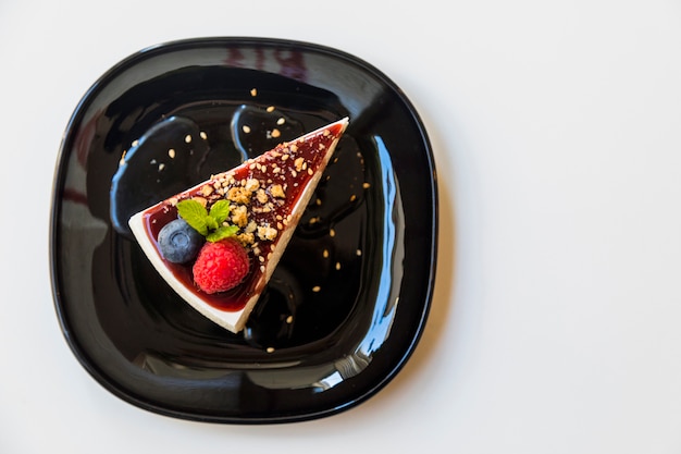 Photo cheesecake fait maison avec de la framboise fraîche; myrtille et menthe pour le dessert sur une plaque noire sur fond blanc