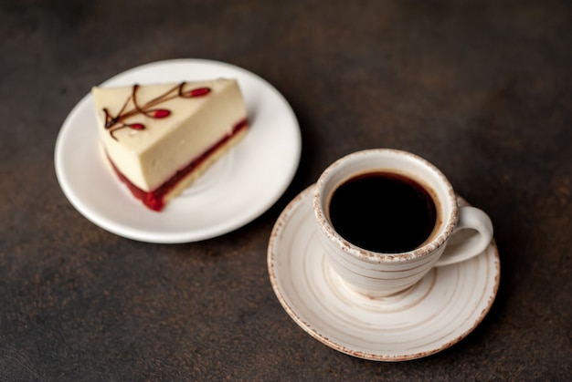 Cheesecake - gâteau sur une plaque blanche et café sur fond de pierre avec copie espace pour votre texte