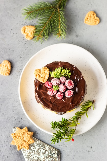 Cheesecake de New York avec ganache au chocolat, framboises et biscuits avec des branches de sapin.