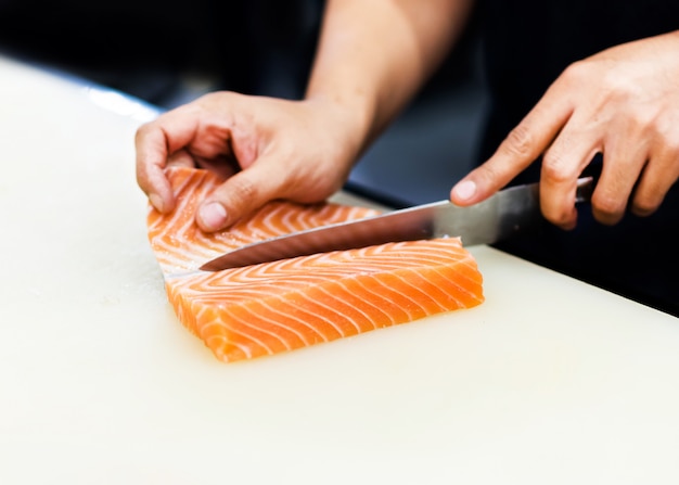 Chef à l'aide d'un couteau pour couper le filet de saumon, le chef coupe le saumon au restaurant