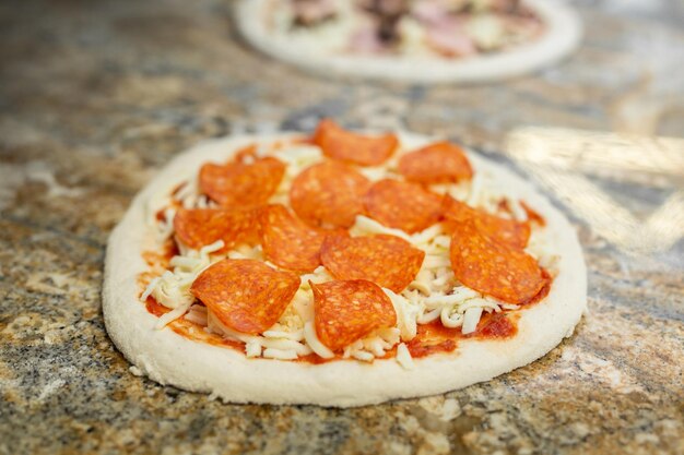 Le chef ajoute du jambon à la pizza avec du salami dans la pizzeria