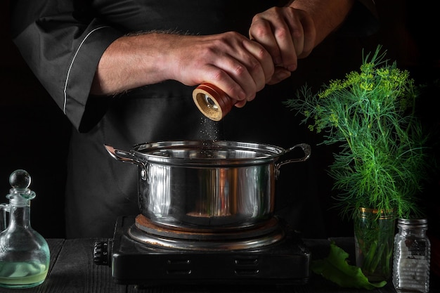 Le chef ajoute du poivre à la casserole tout en préparant des boulettes Environnement de travail sur une cuisine vintage