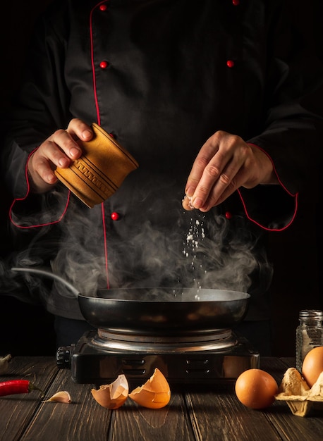 Le chef ajoute du sel pendant la cuisson des œufs dans la poêle