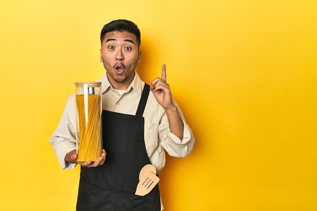 Chef asiatique avec un pot de spaghettis fond de studio jaune ayant une grande idée concept de créativité