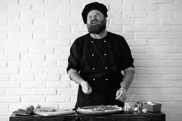 Le chef barbu prépare les repas à table dans la cuisine