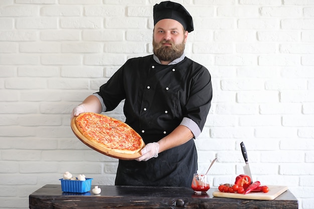 Le chef barbu prépare les repas à table dans la cuisine