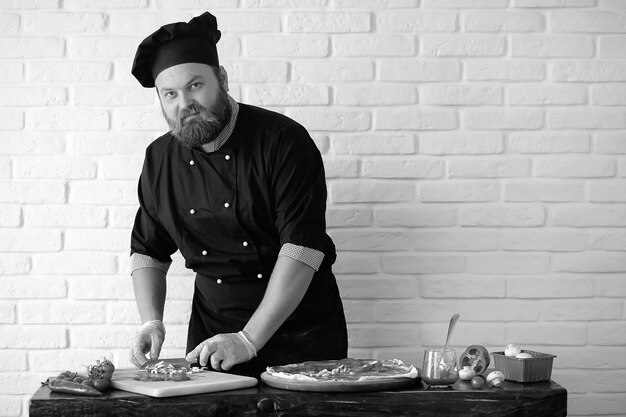 Le chef barbu prépare les repas à table dans la cuisine