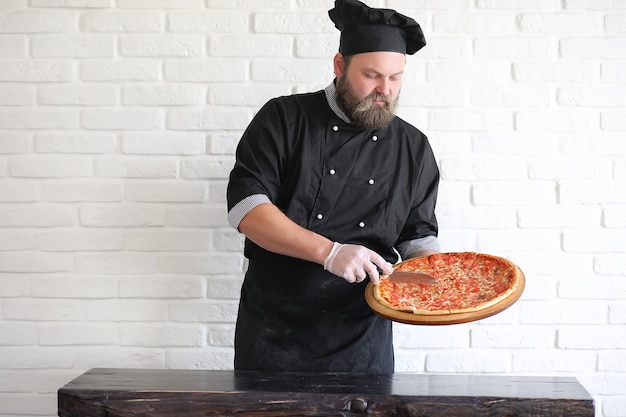 Le chef barbu prépare les repas à table dans la cuisine