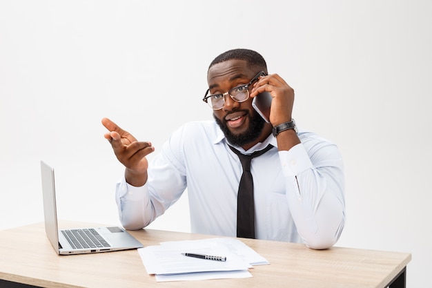 Chef de bureau afro-américaine concentrée, assise au bureau avec un ordinateur portable, lisant des documents importants avec une expression perplexe et tenant la tête de sa main