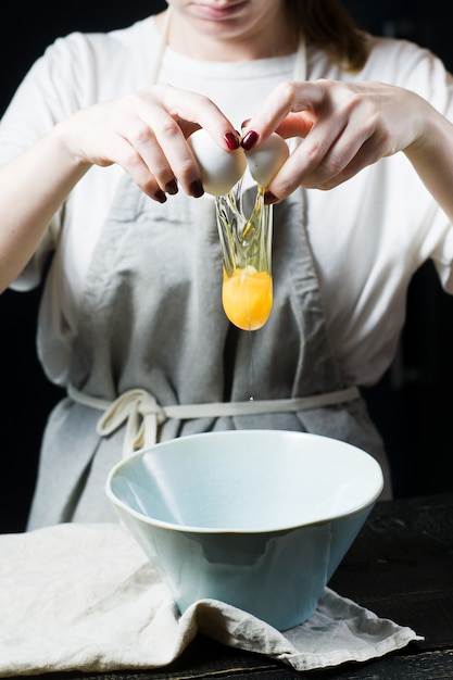 Le chef casse un œuf au-dessus d&#39;un bol et cuit.