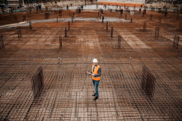 Un chef de chantier est debout sur les charpentes et visite les travaux sur place