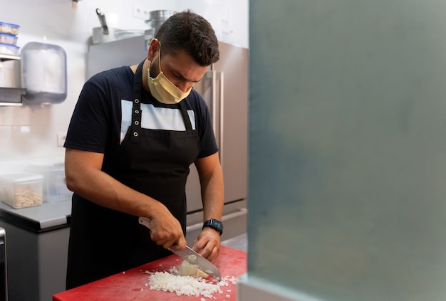 Chef Coupant L'oignon Dans La Cuisine Avec Masque Nouveau Concept Normal