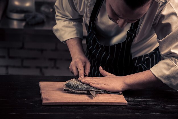 Chef coupant le poisson sur une planche