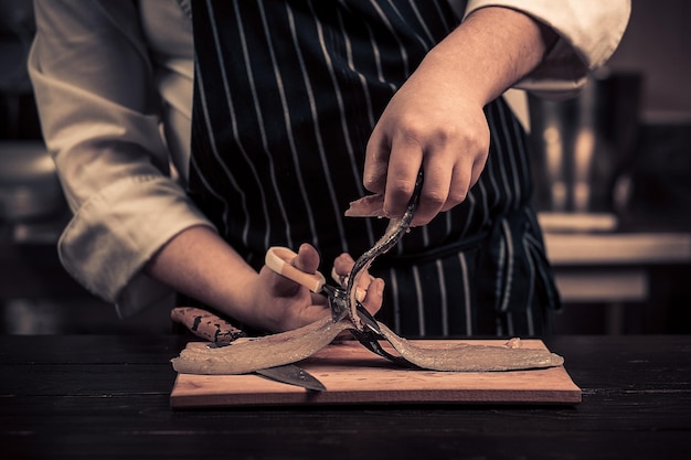 Chef coupant le poisson sur une planche