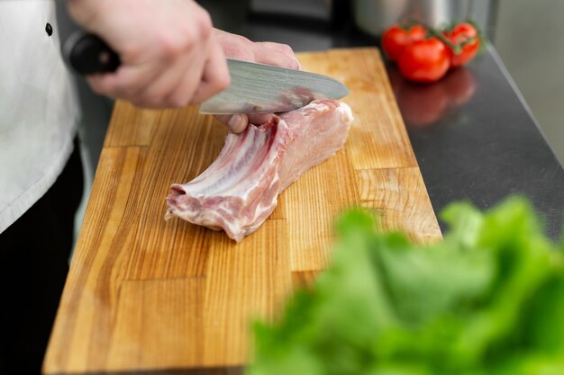 Chef coupant la viande sur une planche en bois