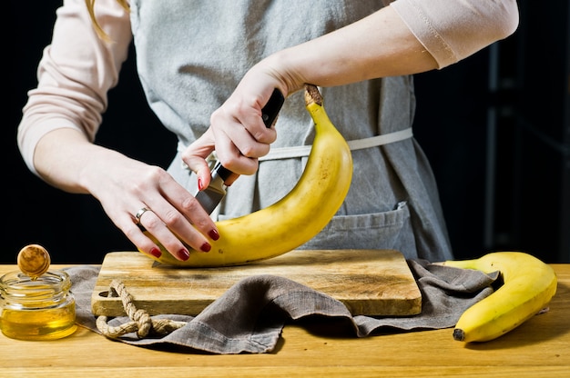 Un chef coupe une banane en tranches. Cuisson des bananes cuites au four.