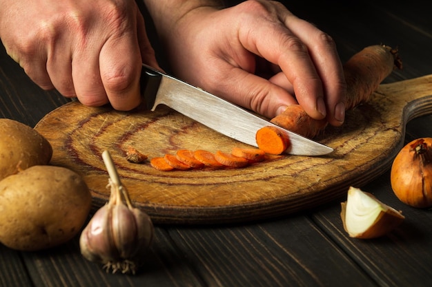 Le chef coupe des carottes pour la soupe aux légumes dans la cuisine du restaurant