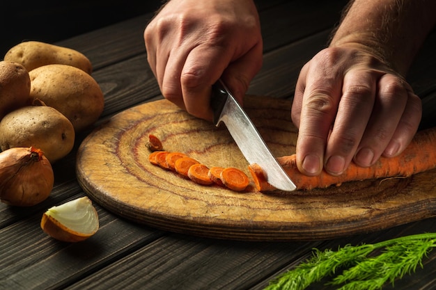 Le chef coupe des carottes pour la soupe aux légumes