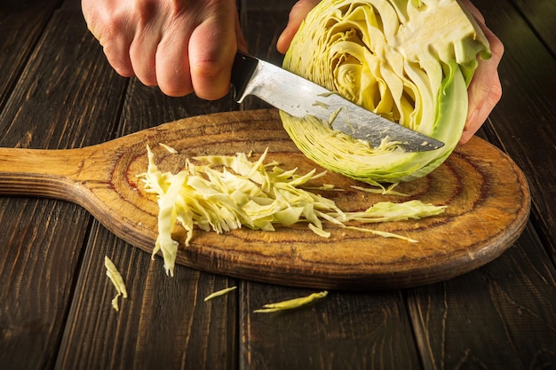 Le chef coupe le chou avec un couteau