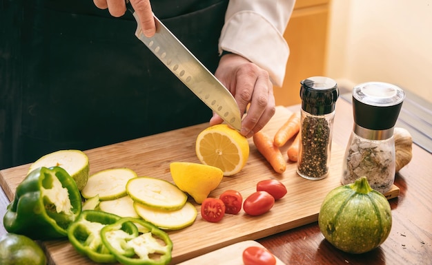 Photo le chef a coupé le citron avec un couteau sur une planche à découper en gros plan légumes frais sur la table de la cuisine