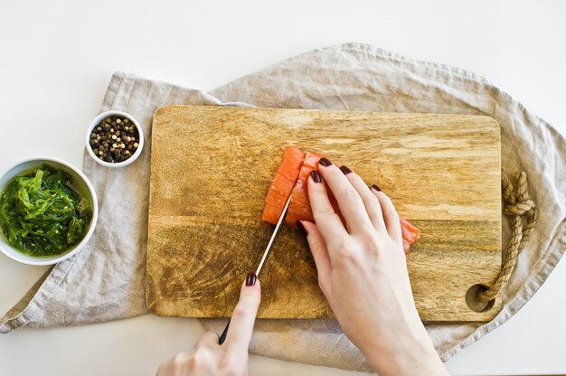 Le chef coupe les filets de saumon sur une planche à découper en bois.