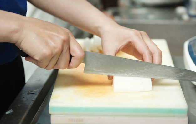 Photo chef coupe légumes sur planche à découper avec un couteau japon