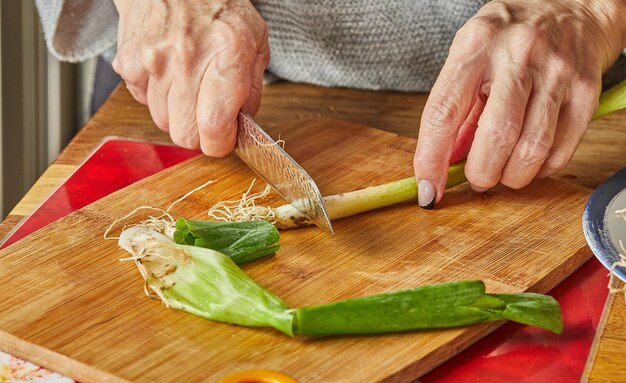 Le chef coupe le poireau en cercles dans la cuisine sur planche de bois