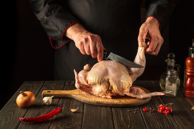 Le chef coupe le poulet à griller cru avant de préparer le dîner