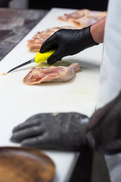 Un chef coupe un poulet sur une planche à découper.