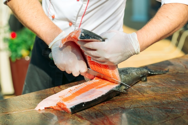 Le chef coupe le saumon sur la table.