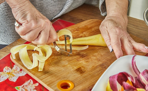 Le chef coupe des tranches de carottes de trois couleurs dans la cuisine sur planche de bois