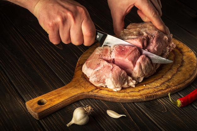 Le chef coupe la viande avec un couteau avant la cuisson