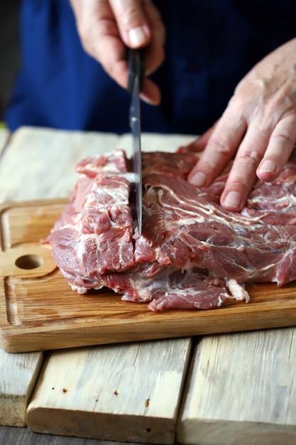 Le chef coupe la viande crue sur la planche à découper