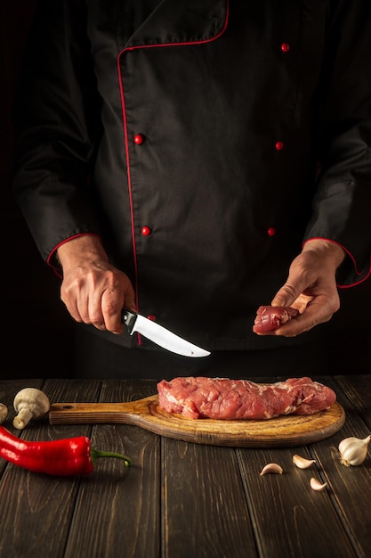 Le chef coupe la viande de veau crue sur une planche à découper avant le barbecue